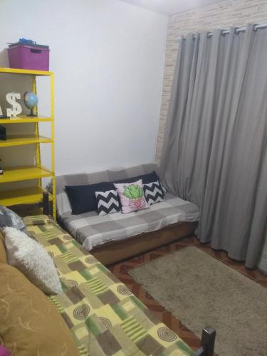 ein Wohnzimmer mit einer Couch mit Kissen darauf in der Unterkunft Kitnet centro São thome hostel in São Thomé das Letras