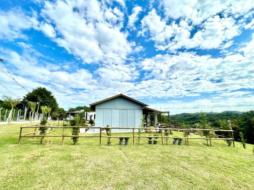 a small white building in a field with a fence at Chácara Passaúna in Curitiba