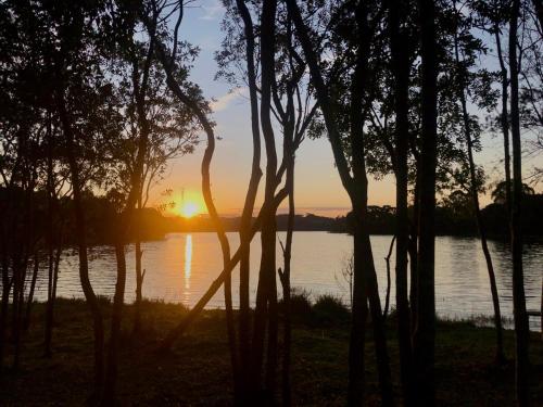 a sunset over a body of water with trees at Chácara Passaúna in Curitiba