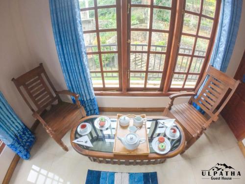 a room with a table and two chairs and a window at Ulpatha Guest House in Hatton