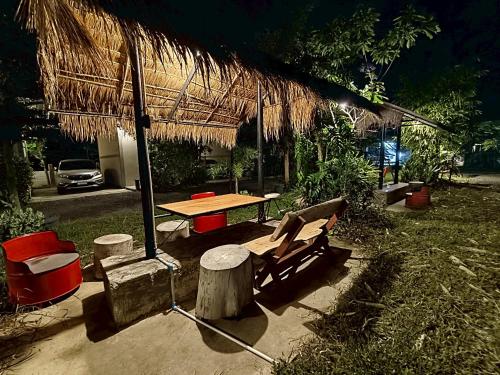 a picnic table and a table with a straw umbrella at เช็คอินรีสอร์ทชัยนาท Check-in resort in Ban Khao Khayai (1)