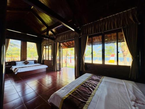a bedroom with two beds in a room with windows at River Homestay in Hàm Tân
