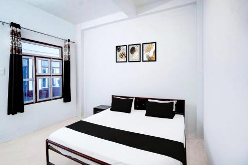 a bedroom with a black and white bed and a window at SPOT ON Hotel Lakshya Ghatampur in Kānpur