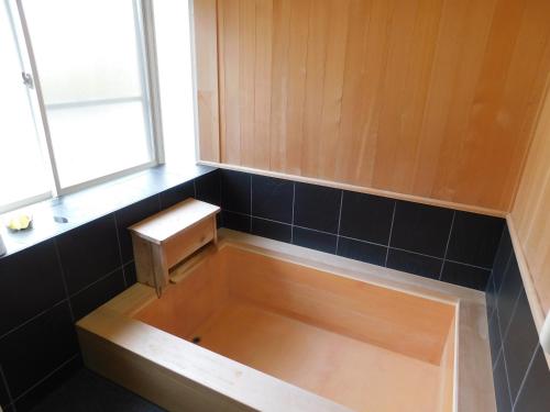 a bath tub with a wooden bench in a bathroom at えびのペンション in Ebino
