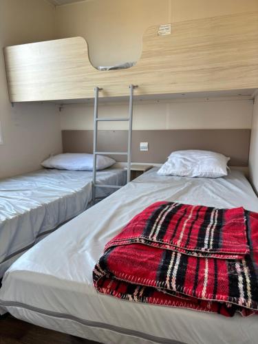 a bedroom with two bunk beds and a red blanket at CAMPING DU PHARE d OPALE MOBILE HOME J10 in Le Portel