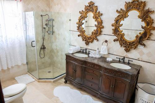 a bathroom with a toilet and two sinks and a shower at Villa La Dueña - Vista Hermosa Luxury Retreat, 5BR Villa with Pool, Swim-Up Bar, Jacuzzi, Chef's Kitchen, Fast Wi-Fi, Full AC, EV Charger and Solar Power, Ideal for Families & Groups in Cancino