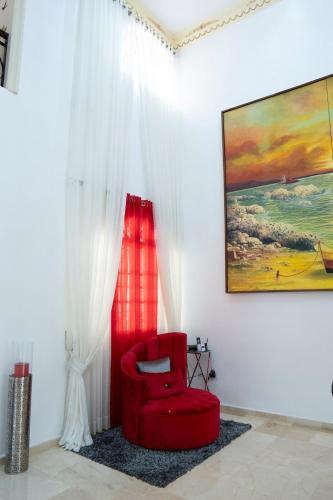 a red chair in a room with a painting at Villa La Dueña - Vista Hermosa Luxury Retreat, 5BR Villa with Pool, Swim-Up Bar, Jacuzzi, Chef's Kitchen, Fast Wi-Fi, Full AC, EV Charger and Solar Power, Ideal for Families & Groups in Cancino