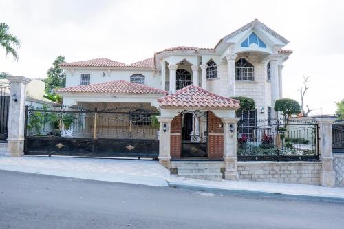 a white house with a gate and a fence at Villa La Dueña - Vista Hermosa Luxury Retreat, 5BR Villa with Pool, Swim-Up Bar, Jacuzzi, Chef's Kitchen, Fast Wi-Fi, Full AC, EV Charger and Solar Power, Ideal for Families & Groups in Cancino