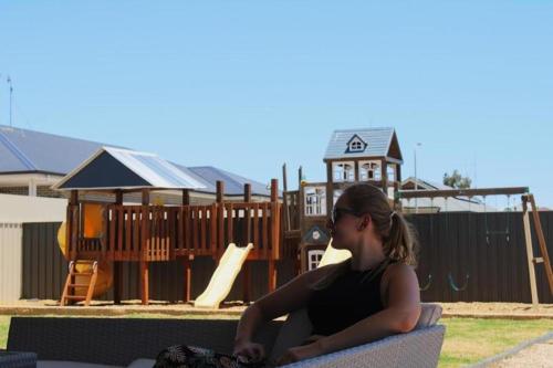 a woman sitting on a bench in front of a playground at The Coastal Crab, Moonta Bay in Port Moonta