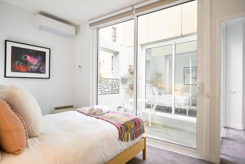 Un dormitorio con una cama y una gran puerta corrediza de vidrio. en Little Collins Central Hideaway - Duplex Penthouse, en Melbourne