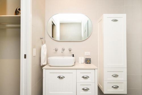Un baño con un lavabo blanco y un espejo. en Little Collins Central Hideaway - Duplex Penthouse, en Melbourne