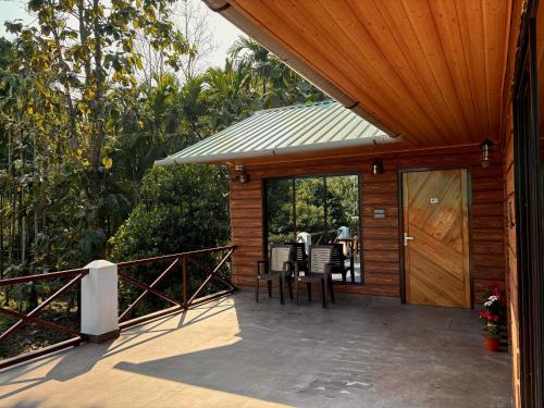 a wooden cabin with a wooden door and chairs on a porch at Villa de hollong in Mādāri Hāt