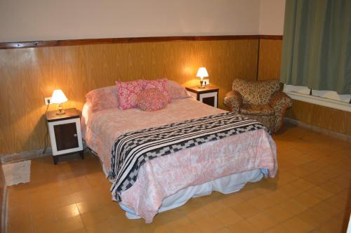 a bedroom with a bed and a chair and two lamps at Hotel Mallorca in Mendoza