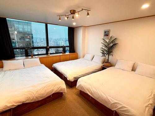 two beds in a room with a large window at 18 Hongik Univ Best location city view in Seoul