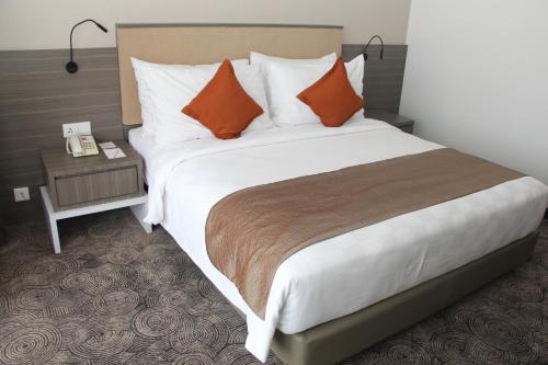 a large bed with orange pillows in a hotel room at Swiss-Belhotel Borneo Samarinda in Samarinda