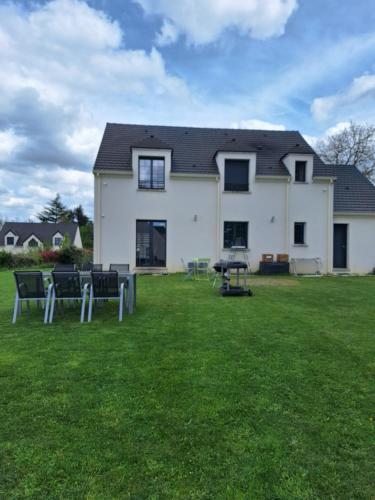 a house with chairs and a table in the yard at Belle Maison Récente in Neauphle-le-Château