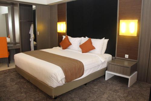 a bedroom with a large bed with orange pillows at Swiss-Belhotel Borneo Samarinda in Samarinda