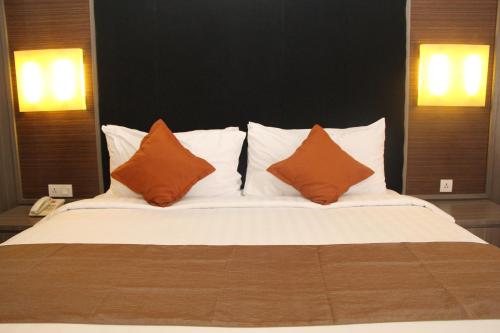 a large bed with orange pillows on top of it at Swiss-Belhotel Borneo Samarinda in Samarinda