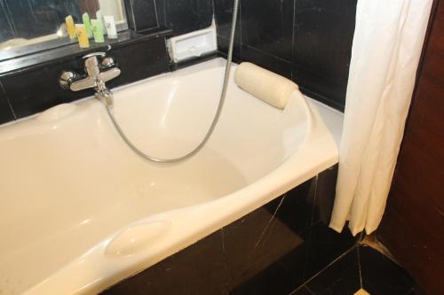 a bath tub with a faucet in a bathroom at Swiss-Belhotel Borneo Samarinda in Samarinda