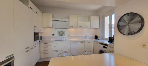 une grande cuisine blanche avec une grande horloge murale dans l'établissement Spacious apartment, center, close to beach and train station, à Saint-Raphaël