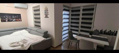 a bedroom with a couch and a desk and a table and a tableablish at City apartman Modrica in Modriča