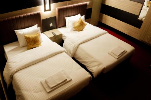 two beds in a hotel room with white sheets and pillows at Garden View Villa in Rājshāhi