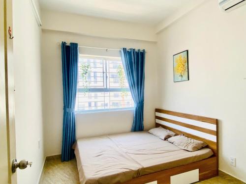 una camera da letto con un letto con tende blu e una finestra di Kate's house Nha Trang - Apartment 60m2 2BR 2Bath, 5 min to beach a Nha Trang