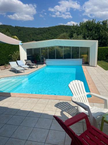 een zwembad met twee stoelen en een huis bij L'Olivier Tropical in Muret