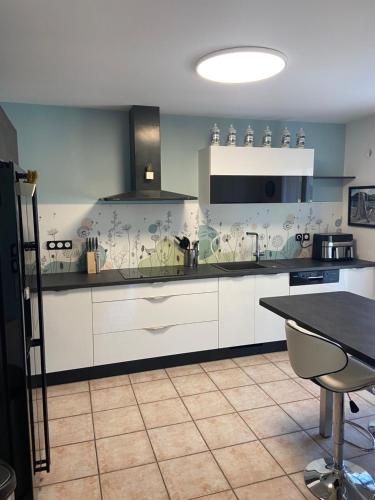 une cuisine avec des armoires blanches et une table à l'intérieur dans l'établissement L'Olivier Tropical, à Muret