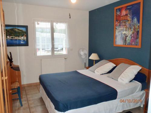 een slaapkamer met een groot bed met blauwe muren bij L'Olivier Tropical in Muret