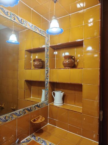 a yellow tiled bathroom with shelves and lights at Casa rural entera en Parque Natural de los Puertos in Alfara de Carles