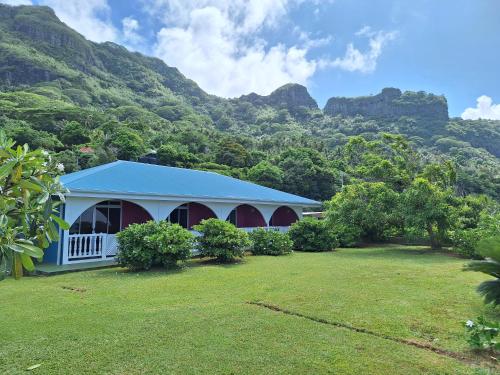 a white building with a mountain in the background at Pension Tautiare Village in Maupiti