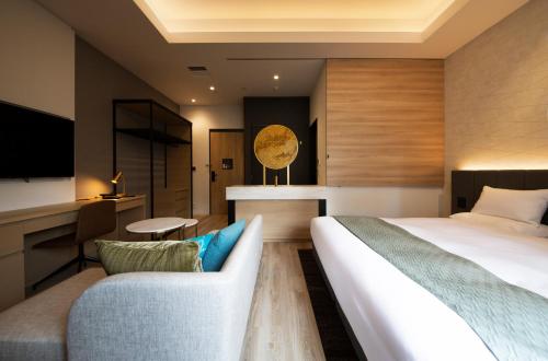 a hotel room with a bed and a couch at Nikko Style Nagoya in Nagoya