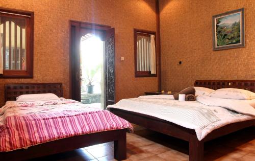 two twin beds in a room with a window at Bella House Monkey Forest in Ubud