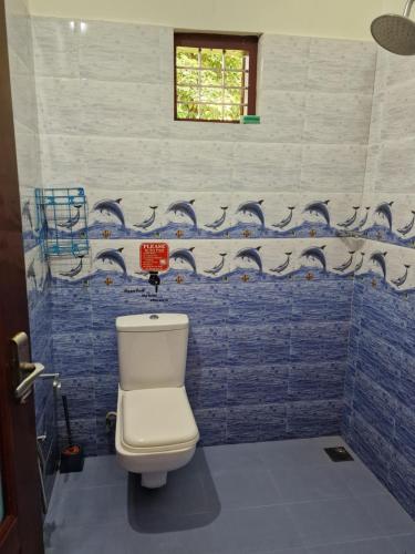 a bathroom with a toilet and a blue tiled wall at Short term 3 bedroom house in Chengannūr