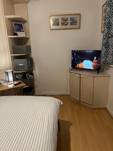 a bedroom with a bed and a television on a cabinet at The Bungalow by SJP - Double Room in Kettering