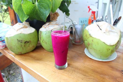 a drink in a glass sitting on a table with two coconuts at Puunee Wild River Villa's Borobudur in Borobudur
