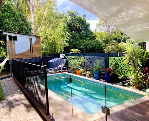 a swimming pool in a backyard with a black fence at Sandy Feet Retreat - 50m from Four Mile Beach in Port Douglas