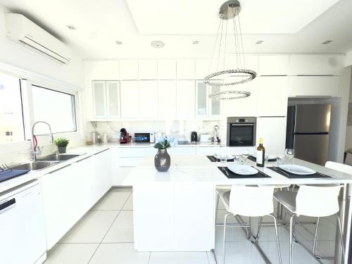 a white kitchen with a large island with white cabinets at Wealthystays Duplex in the Heart of Nicosia in Nicosia