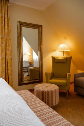 a hotel room with a mirror and a chair at Hotel Birke, Ringhotel Kiel in Kiel