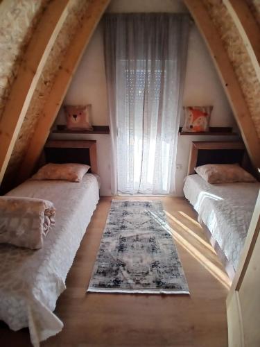 a attic room with two beds and a window at D&N place - forest house Zabljak in Žabljak
