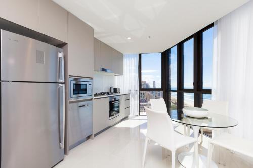 a kitchen with stainless steel appliances and a white refrigerator at Rhapsody Resort - Official in Gold Coast