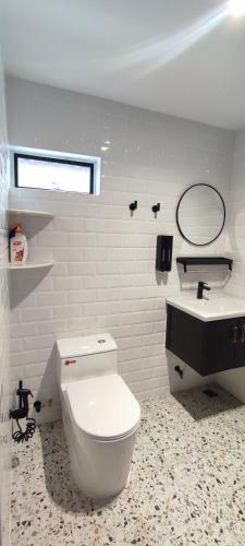 a white bathroom with a toilet and a sink at Akasea Sojourn in Jitra