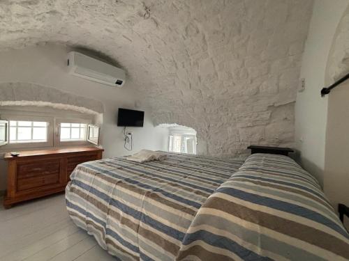 a bedroom with a bed and a stone wall at Casetta Arco Casavola in Martina Franca