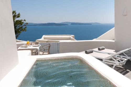 a balcony with a swimming pool and a table and chairs at Anemomilos in Oia