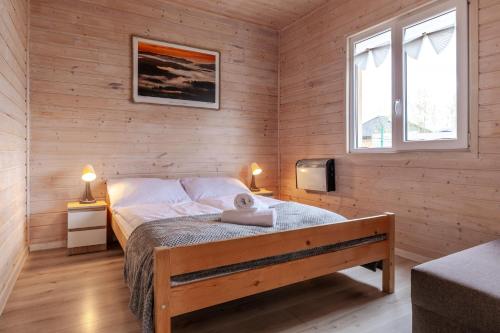 a bedroom with a bed and two windows at Karkonoskie Sny - Domki z widokiem na Karkonosze in Wojcieszyce