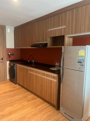 a kitchen with wooden cabinets and a stainless steel refrigerator at Spacious Bedroom- 2 mins from Train Station in Bangkok