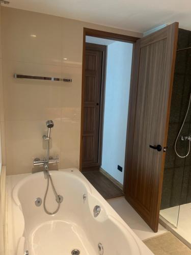 a bath tub in a bathroom with a shower at Spacious Bedroom- 2 mins from Train Station in Bangkok