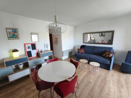 un salon avec une table et un canapé bleu dans l'établissement Appartement T2 Bord de Mer - Maria Beach, à Santa-Lucia-di-Moriani