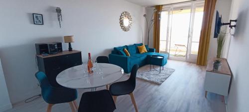 un salon avec une table et un canapé bleu dans l'établissement Nice, vue mer et panoramique, à Nice